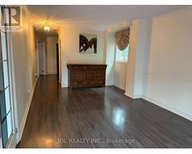 A hallway with wood flooring and a wooden cabinet under a painting.