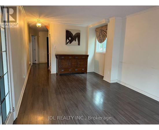 A hallway with wood flooring and a wooden cabinet under a painting.
