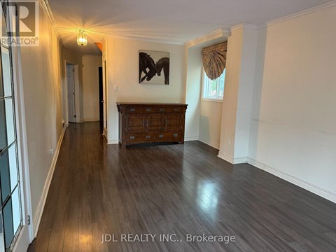 A hallway with wood flooring and a wooden cabinet under a painting.
