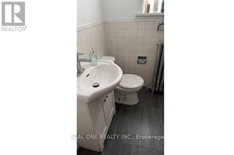 A white toilet with a white sink in a small bathroom.