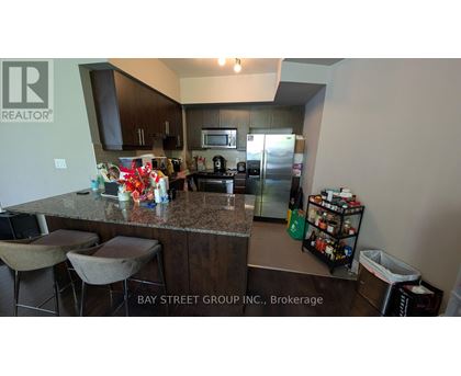 A kitchen with granite countertops and a bar area with stools.