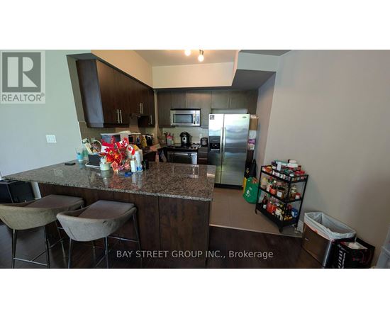 A kitchen with granite countertops and a bar area with stools.