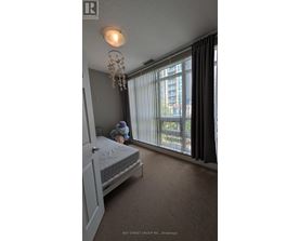 A bedroom with a bed, a chandelier, and a window with curtains.