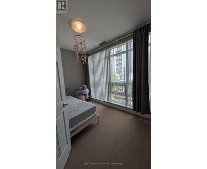 A bedroom with a bed, a chandelier, and a window with curtains.