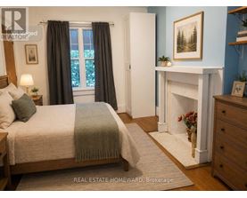 A bedroom with a bed, a fireplace, and a painting on the wall.