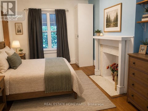 A bedroom with a bed, a fireplace, and a painting on the wall.