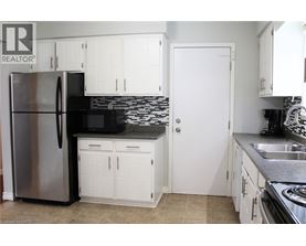 A kitchen with white cabinets and a stainless steel refrigerator.