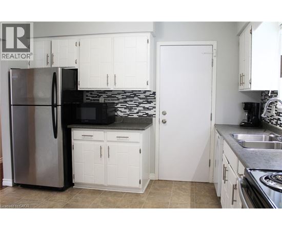 A kitchen with white cabinets and a stainless steel refrigerator.