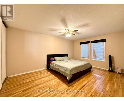 A bedroom with a bed, a ceiling fan, and a window with blinds.