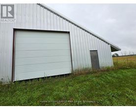 A large white metal building with a closed grey roller shutter door.