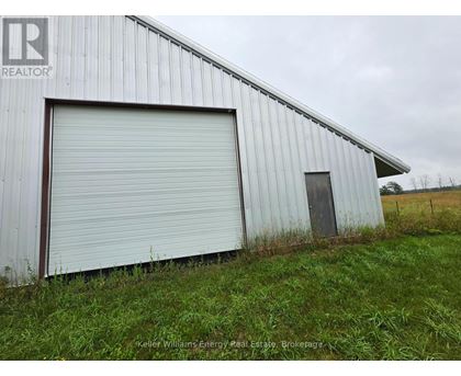 A large white metal building with a closed grey roller shutter door.