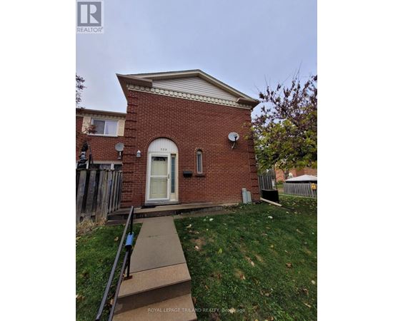 A small red brick house with a white door and a satellite dish on the roof.