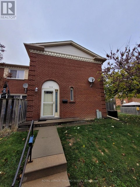 A small red brick house with a white door and a satellite dish on the roof.