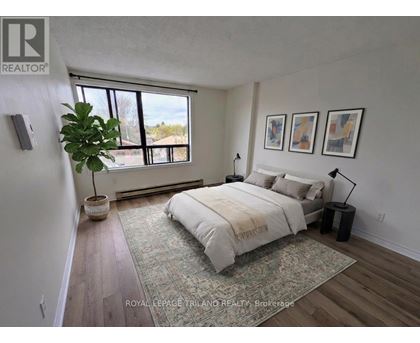 A bedroom with a large bed and a potted plant.