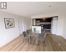 A dining room with a glass table and grey chairs.