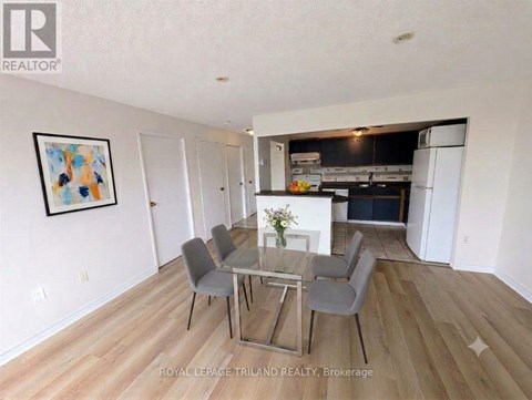 A dining room with a glass table and grey chairs.
