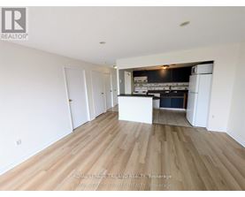 A spacious room with wooden flooring and white walls.