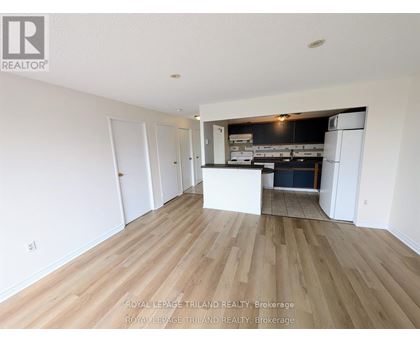 A spacious room with wooden flooring and white walls.