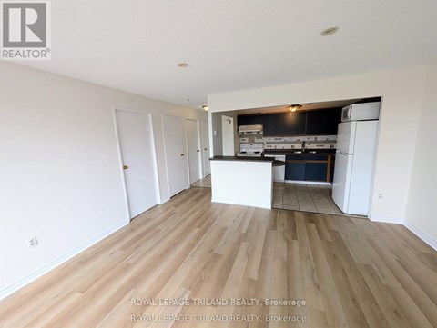 A spacious room with wooden flooring and white walls.