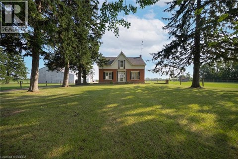 A house with a brown roof and white trim is surrounded by trees.