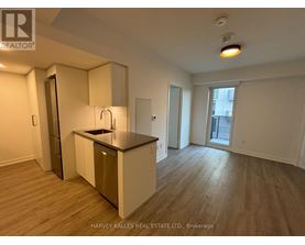 A kitchen with a sink and a refrigerator in a room with wood flooring.