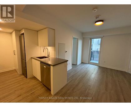 A kitchen with a sink and a refrigerator in a room with wood flooring.