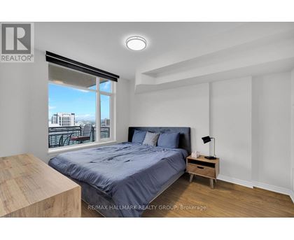 A bedroom with a large bed and a view of the city through the window.