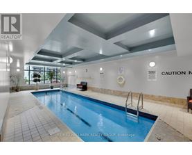 A swimming pool inside a building with a caution sign on the wall.
