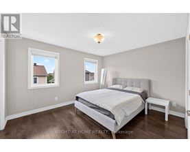 A bedroom with a large bed and a window overlooking a house.