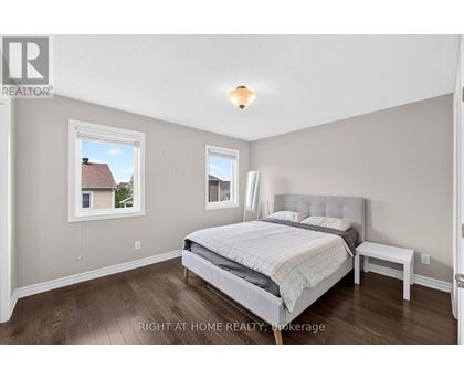 A bedroom with a large bed and a window overlooking a house.