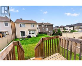 A wooden deck overlooks a grassy area with houses in the background.