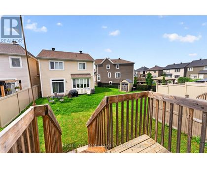 A wooden deck overlooks a grassy area with houses in the background.