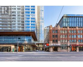 A modern building with a glass facade is in the background, while a Loblaws grocery store is in the foreground.