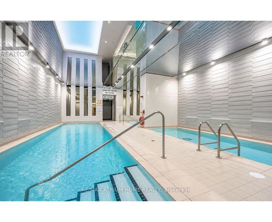 A swimming pool inside a building with a glass wall.