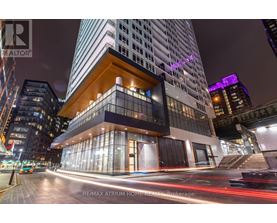 A modern building with a glass facade and a wooden balcony is illuminated at night.