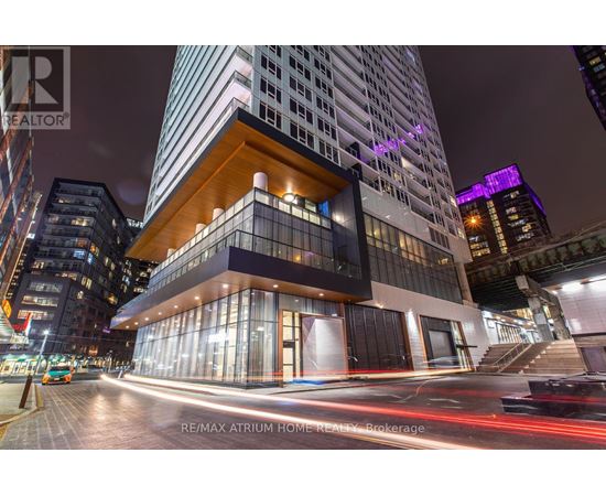A modern building with a glass facade and a wooden balcony is illuminated at night.