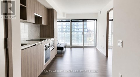 A modern kitchen with wooden cabinets and a large window.