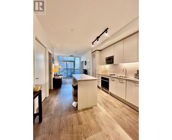 A modern kitchen with white cabinets and a wooden floor.
