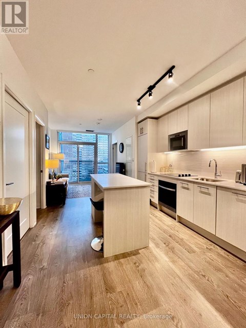 A modern kitchen with white cabinets and a wooden floor.