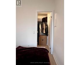A bedroom with a bed and a closet with clothes.