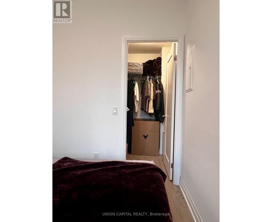 A bedroom with a bed and a closet with clothes.