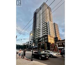 A tall building with a glass facade is the focal point of the image, with people walking and cars parked in front.