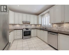A kitchen with white cabinets and a stone backsplash.