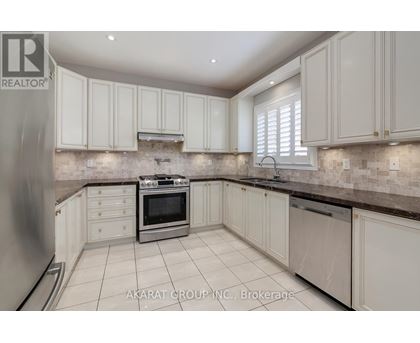 A kitchen with white cabinets and a stone backsplash.