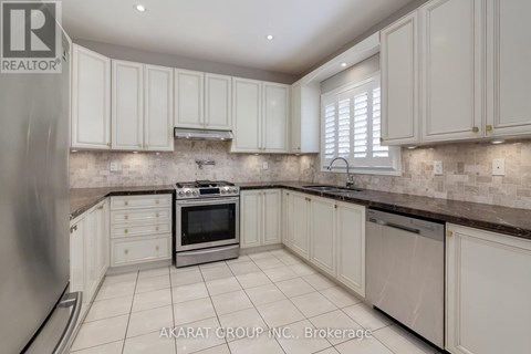 A kitchen with white cabinets and a stone backsplash.
