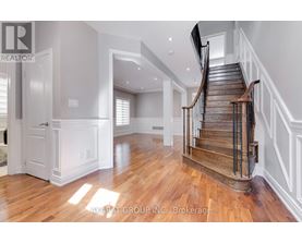 A spacious room with a wooden staircase and white walls.