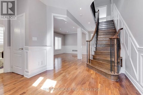 A spacious room with a wooden staircase and white walls.
