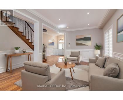 A living room with a staircase and a painting on the wall.