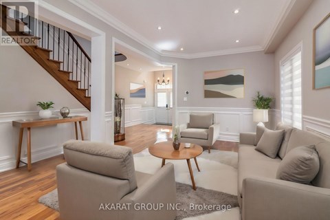 A living room with a staircase and a painting on the wall.