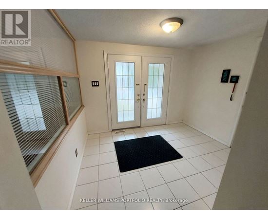 A hallway with a black doormat in front of a white door.